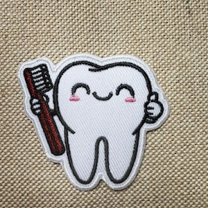 May include: White embroidered tooth with a happy face holding a red toothbrush. The tooth is smiling and giving a thumbs up.