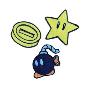 Pode incluir: Patches bordados com símbolos icônicos de videojogos. Inclui uma moeda amarela, uma estrela amarela com olhos e uma bomba azul marinho com chave de corda. Ideais para adicionar um toque de nostalgia gamer a roupas ou acessórios.
