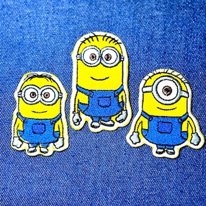May include: Three embroidered patches featuring Minion characters. Each Minion is yellow with blue overalls, black hair, and large, round eyes. The patches are outlined in white and set against a blue denim background.