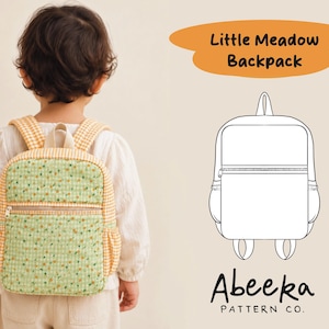 Könnte beinhalten: Ein Rucksack mit einem grünen Blumenstoff-Einsatz, gelb-weißem Vichy-Karo-Besatz, einer vorderen Reißverschlusstasche und Seitentaschen. Das Bild enthält den Text Little Meadow Backpack und Abeeka Pattern Co. neben einer Strichzeichnung.