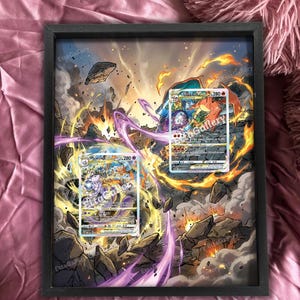 Op de afbeelding: Ingelijste kunst met twee Pokémon-ruilkaarten tegen een geïllustreerde achtergrond van een explosie met rotsen en vuur. De kaarten zijn gecentreerd, met de tekst "Etta Gallery" zichtbaar.