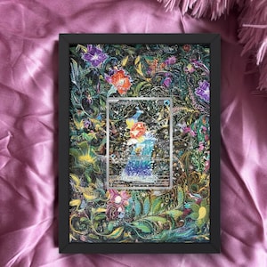 Può includere: Opera d'arte con cornice nera con un colorato design floreale e una carta al centro. La carta non è inclusa. L'opera presenta un vivace mix di tonalità verdi, viola e arancioni, creando un'estetica vivace e artistica.