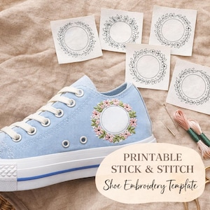 May include: A pale blue canvas trainer with white laces and sole, decorated with floral embroidery. Several paper templates with wreath designs are scattered around the trainer. The text "PRINTABLE STICK & STITCH Shoe Embroidery Template" is visible.