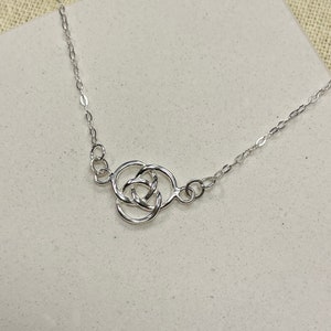 May include: A silver necklace featuring a Celtic knot pendant. The knot is formed from three interlocked circles.