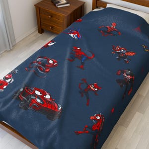 May include: A navy blue bedspread featuring various cartoon depictions of Spider-Man in different forms, including a car, a dinosaur, and a cat. The illustrations are primarily red and black, with white accents.