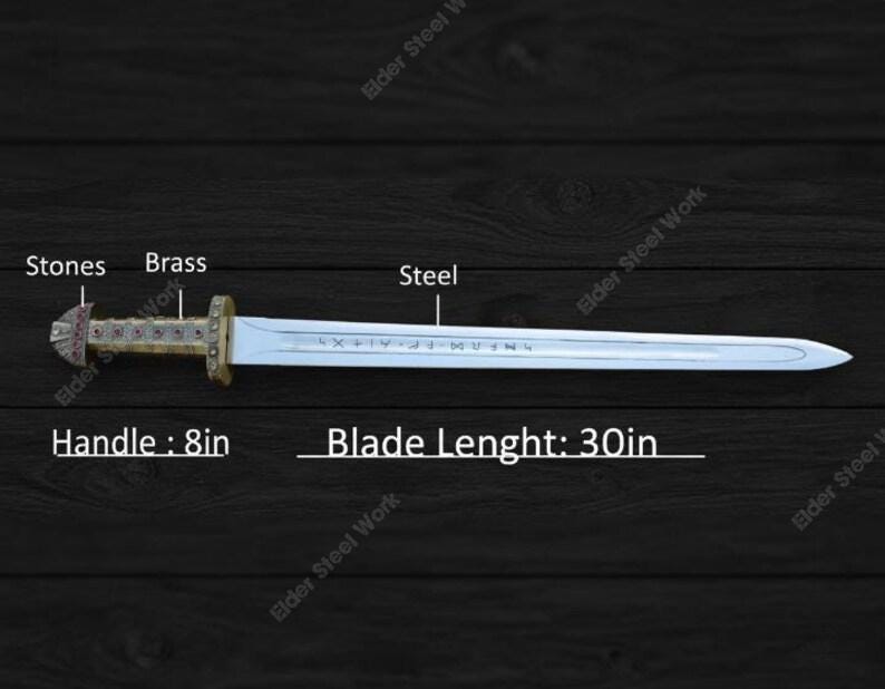 May include: A steel sword with a brass handle and stone accents. The blade is 30 inches long, and the handle is 8 inches. The sword has engraved text on the blade.