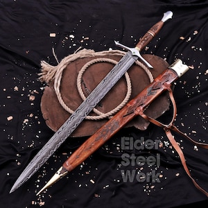 May include: A Damascus steel sword with a patterned blade, a wooden hilt featuring metal accents, and a matching brown leather scabbard with brass fittings. The scabbard is embossed with intricate designs and includes leather straps for carrying.