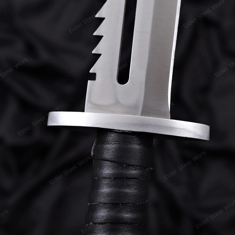 May include: Close-up of a survival knife with a polished steel blade and a serrated edge. The knife features a black, wrapped handle and a silver guard. The blade has the text "Keel" etched on it.