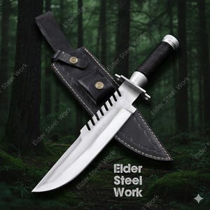 May include: A large, silver survival knife with a serrated blade and black handle, resting in a black leather sheath. The sheath has a belt loop and a small pouch. The text "Elder Steel Work" is visible.