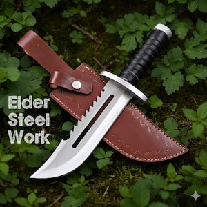 May include: A survival knife with a serrated blade and a black handle, resting in a brown leather sheath. The knife has a silver blade and a silver guard. The sheath is embossed with a pattern. The text "Elder Steel Work" is visible.
