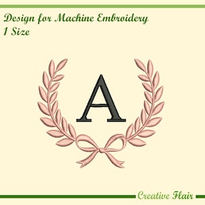 Può includere: Design per ricamo a macchina con la lettera "A" nera, circondata da una corona d'alloro e un fiocco rosa. Il testo "Design for Machine Embroidery" e "1 Size" sono in alto. Le parole "Creative Flair" sono in basso.