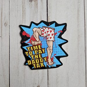 May include: A die-cut sticker featuring a comic book style illustration of legs wearing white boxer shorts with red hearts. The background is a blue starburst with red splatters and the yellow text reads: TIME TO PAY THE DADDY TAX.