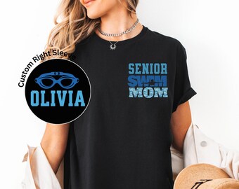 Peut inclure: T-shirt noir avec le texte bleu "SENIOR SWIM MOM". Un motif circulaire sur la manche gauche représente des lunettes de natation et le nom "OLIVIA" en bleu. Le t-shirt est de coupe confortable.