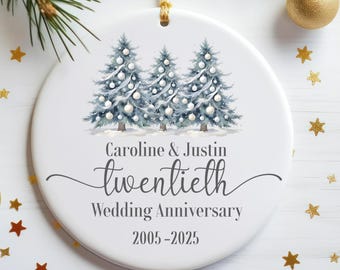 May include: White ceramic Christmas ornament with a watercolor design of three decorated Christmas trees. The ornament is personalized with the names "Caroline & Justin" and the text "Twentieth Wedding Anniversary 2005-2025".