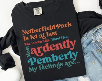 May include: A black long-sleeve t-shirt featuring multi-colored text that reads: Netherfield Park is let at last, She is tolerable, Hand flex, Most ardently, Pemberly, My feelings are. The shirt has a Comfort Colors brand tag at the neck.