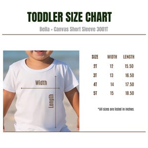 Puede incluir: Camiseta blanca para ni&ntilde;os peque&ntilde;os con una tabla de tallas. La tabla enumera las tallas 2T a 5T, con medidas de ancho y largo en pulgadas. El texto "TODDLER SIZE CHART" est&aacute; en la parte superior.