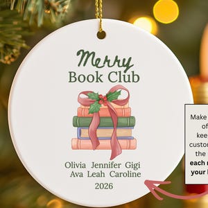 Pode incluir: Um ornamento redondo de cer&acirc;mica branca com o texto verde Merry Book Club sobre uma ilustra&ccedil;&atilde;o de uma pilha de quatro livros atados com uma fita vermelha e azevinho. Abaixo dos livros est&atilde;o os nomes Olivia, Jennifer, Gigi, Ava, Leah, Caroline e 2026.
