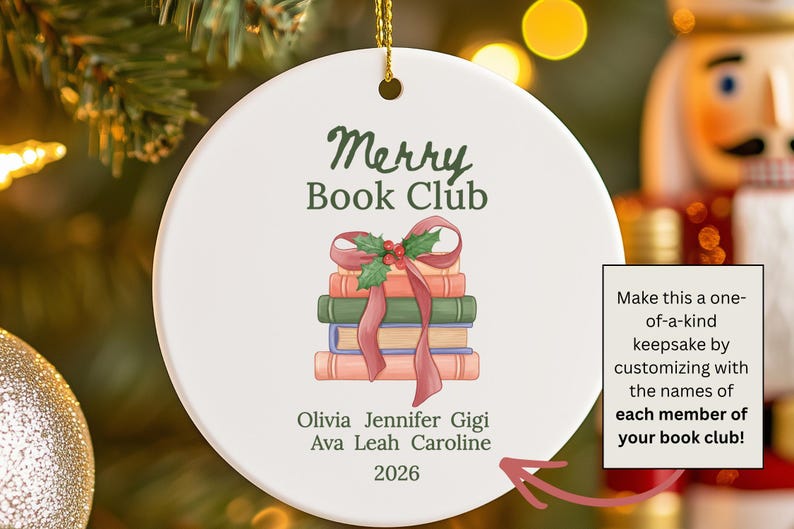 Pode incluir: Um ornamento redondo de cer&acirc;mica branca com o texto verde Merry Book Club sobre uma ilustra&ccedil;&atilde;o de uma pilha de quatro livros atados com uma fita vermelha e azevinho. Abaixo dos livros est&atilde;o os nomes Olivia, Jennifer, Gigi, Ava, Leah, Caroline e 2026.