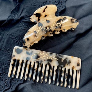 May include: Two tortoiseshell hair accessories: a large claw clip with the name "Kendall" engraved on it and a comb with the name "Elsie" engraved on it.