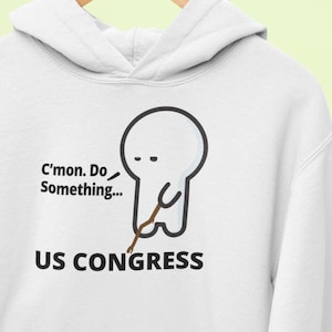May include: White hoodie with a cartoon illustration of a stick figure with a sad expression holding a stick. The text "C'mon. Do Something... US CONGRESS" is printed below the illustration.