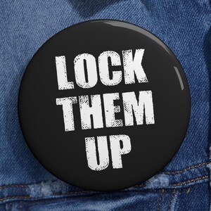 May include: A round, black button with the white text "LOCK THEM UP". The button is set against a denim background.