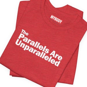 Könnte beinhalten: Rotes T-Shirt mit weißem Text, der "The Parallels Are Unparalleled" lautet, und einem kleinen weißen Etikett mit der Aufschrift "MYBODY".