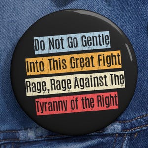 Może przedstawiać: Czarny, okrągły guzik z napisem "Do Not Go Gentle Into This Great Fight Rage, Rage Against The Tyranny of the Right" w kolorze białym, niebieskim, pomarańczowym, beżowym i czerwonym. Guzik ma błyszczące wykończenie.