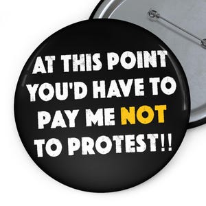 May include: A black button with the text "AT THIS POINT YOU'D HAVE TO PAY ME NOT TO PROTEST!!" in white, with the word "NOT" in yellow. The button has a silver pin back.