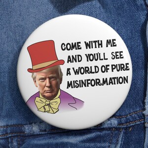 May include: A white button with a cartoon image of Donald Trump wearing a purple suit, a yellow bow tie, and a red and white top hat. The text on the button reads "Come with me and you'll see a world of pure misinformation."