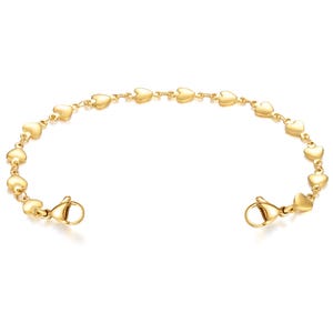 May include: A gold-colored bracelet featuring a series of heart-shaped charms. The bracelet has a delicate chain and a clasp closure. The hearts are evenly spaced along the chain, creating a romantic and elegant design.