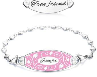 May include: A silver bracelet with a pink enamel center engraved with the name "Jennifer" and a decorative floral pattern. The bracelet has a chain of heart-shaped links and a separate tag that reads "True friend".
