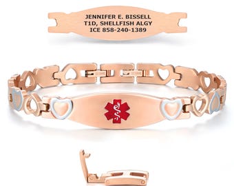 May include: Rose gold medical ID bracelet with a heart-shaped link design. The central plate features a red medical symbol and the text "JENNIFER E. BISSELL T1D, SHELLFISH ALGY ICE 858-240-1389". Includes a separate rose gold plate with the same text and a clasp.