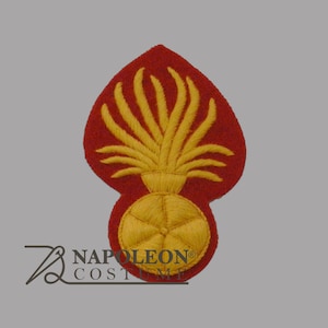 May include: A red and yellow embroidered patch featuring a stylized flame design. The patch has a red background with a yellow flame and a circular yellow base. The patch is likely a military or historical emblem.