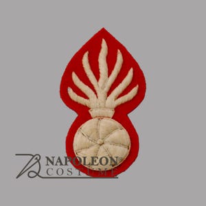 May include: An embroidered patch in red and cream, featuring a flame design. The patch has a red backing with a cream-coloured flame and a spherical base. It is likely a military or historical emblem, possibly for a uniform.