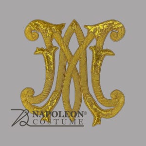 May include: A gold embroidered patch featuring an ornate, stylized monogram of the letters M and E intertwined with decorative flourishes. The design is rendered in metallic gold thread with visible stitching. The text NAPOLEON COSTUME is below.