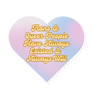 Könnte beinhalten: Ein rosa-blauer herzförmiger Aufkleber mit dem Text "Trans & Queer People Have Always Existed & Always Will" in einer gelben Retro-Schrift.