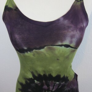 May include: A tie-dye tank top with a green, purple, and black swirl pattern. The tank top has a scoop neck and thin straps.