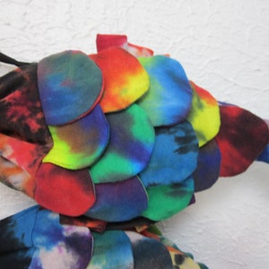 May include: A colorful tie-dye fish made of fabric with a rainbow pattern. The fish has a tail and scales.