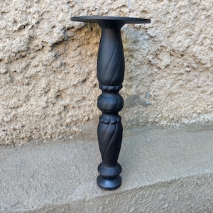 May include: A matte black furniture leg featuring a vertical spiral carved design along its cylindrical body. The leg has a flat circular mounting plate at the top and a rounded base, showcasing a uniform dark finish throughout its entire structure.