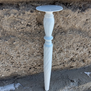 May include: A white, decorative table leg with a round top and a spiraled design. The leg is made of a solid material and is designed to support a table. The leg is approximately 20 inches tall.