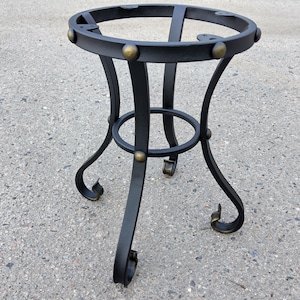 Pode incluir: Uma base de mesa em ferro forjado preto com um tampo circular e três pernas curvas. As pernas são conectadas por uma cinta circular e adornadas com detalhes em tom de latão. Projetado para um tampo de mesa redondo.