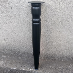 May include: A matte black furniture leg featuring a tapered cylindrical body with a rounded, bulbous section near the top and a flat circular mounting plate at the summit. The leg has a smooth finish and a simple, functional design.