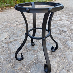Può includere: Portavaso in ferro battuto nero con piano circolare e design decorativo a gambe curve. Il supporto ha una base robusta e un anello al centro per un maggiore sostegno. Il supporto è alto circa 61 cm.