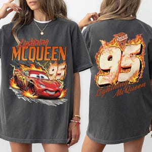 May include: Dark gray Lightning McQueen t-shirt. The front features a graphic of the red race car with the number 95 and the text "Lightning McQueen". The back of the shirt has the number 95 in flames and the text "Lightning McQueen".
