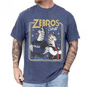 May include: Navy blue t-shirt with a graphic of two zebras. One is dressed as a police officer, the other in a jacket. The text "ZEBROS" is above the zebras, with "Zebros" in script below.