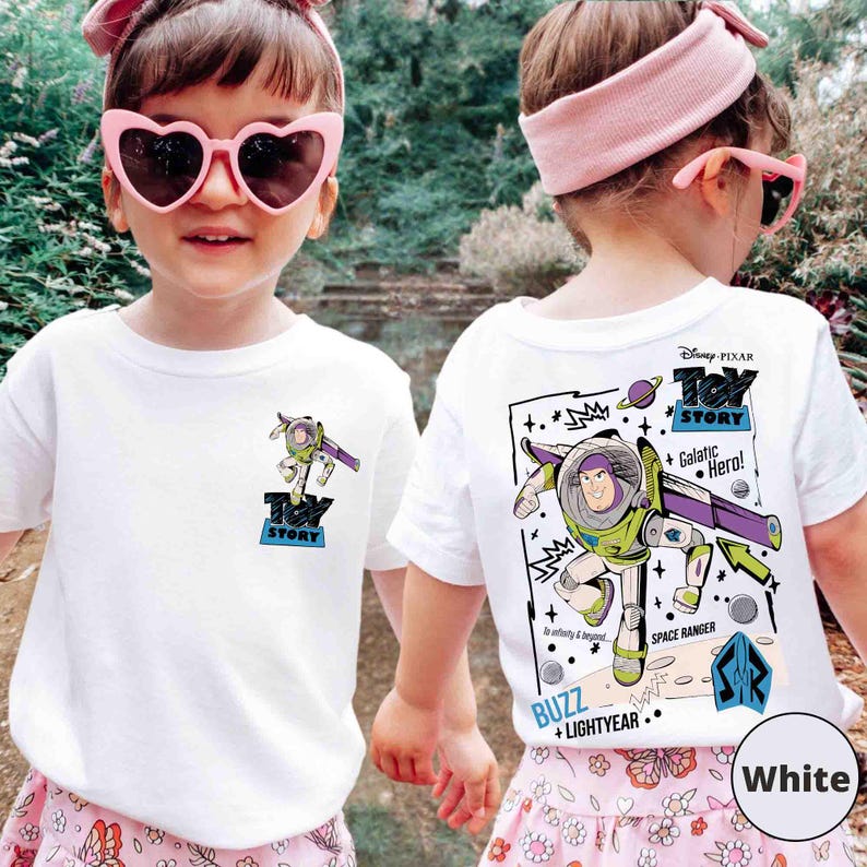 K&ouml;nnte beinhalten: Wei&szlig;e T-Shirts mit einem Buzz Lightyear-Motiv aus Toy Story. Die Vorderseite hat ein kleines Design, die R&uuml;ckseite ein gr&ouml;&szlig;eres mit "Galactic Hero!" und "Space Ranger". Das Disney Pixar-Logo ist ebenfalls sichtbar.