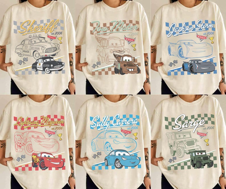 May include: Cream-coloured t-shirts with cartoon car designs, including "Sheriff," "Tow Mater," and "Jackson Storm." Each shirt displays a different car graphic, text, and the year "2006" or "2005."