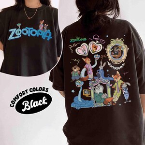 Puede incluir: Camiseta negra con la palabra "Zootopia" en azul y personajes de dibujos animados. La parte trasera de la camiseta tiene un gr&aacute;fico m&aacute;s grande con m&aacute;s personajes y el logotipo de "Zootopia". La camiseta est&aacute; etiquetada como "Comfort Colors".