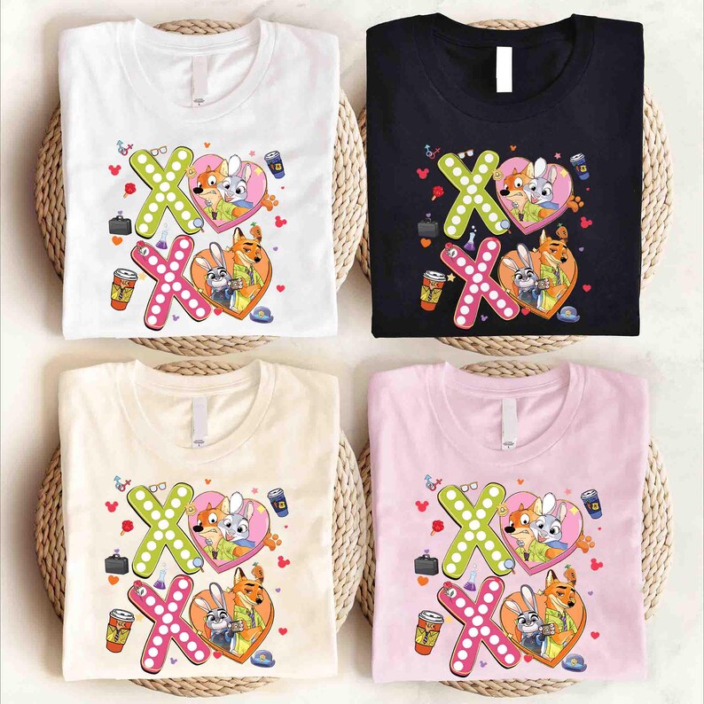 May include: Four t-shirts in white, black, beige, and pink, each featuring a graphic design with the characters from Zootopia. The design includes the letters "XO" with a heart, and other small illustrations.