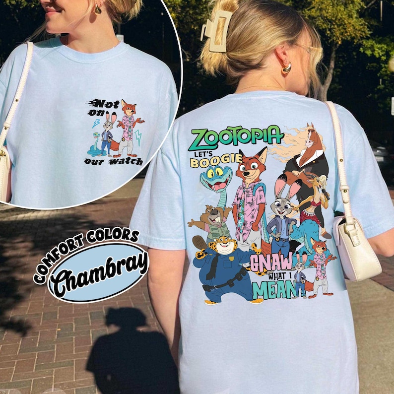 May include: Light blue Comfort Colors Chambray t-shirt featuring a graphic of characters from the animated film Zootopia. The front of the shirt has the text "Not on our watch". The back of the shirt has the text "Zootopia" and "Let's Boogie".